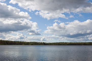 Lake in-field. A bright summer sun. White clouds.