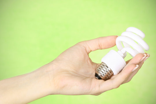 female hand holding a CFL bulb on green background