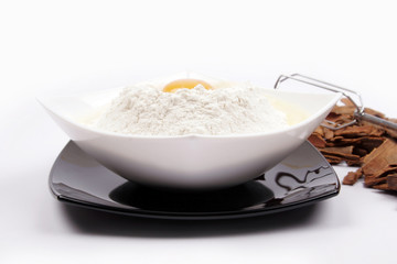 White plate with egg on top of a black plate on white background
