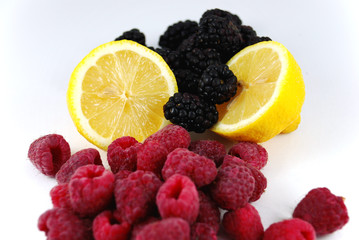 Lemon with black berries and raspberries on a white back ground