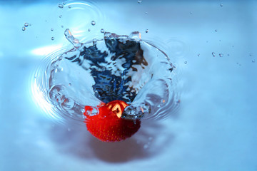 strawberry falling into water, splashing water. 