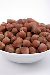 Hazelnuts on a white bowl. White background