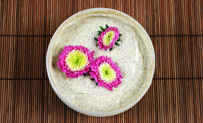Spa and beauty products - body scrub with pink flowers.