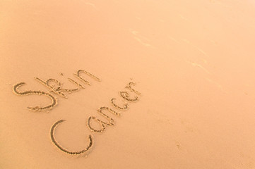 Fototapeta na wymiar Rak skóry napisany w piasku na złotej plaży