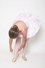 Young dancer tying her ballet shoe ribbon