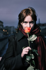 Portrait of a young redhead woman with fresh red rose