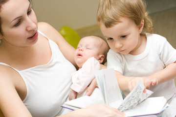 Mother of two babies, reading a book