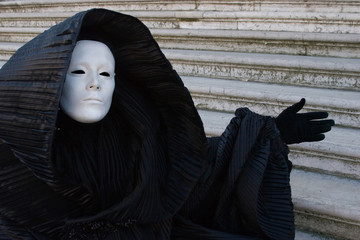 Figure in black hood and white mask, gesturing. Venice