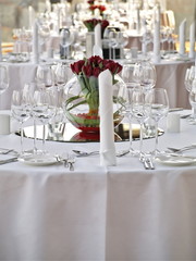 Reihe festlicher Esstische mit eleganten roten Rosen auf runden Vasen am Spiegel Mittelstück