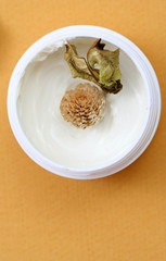 Spa essentials (cream and flowers) isolated on yellow