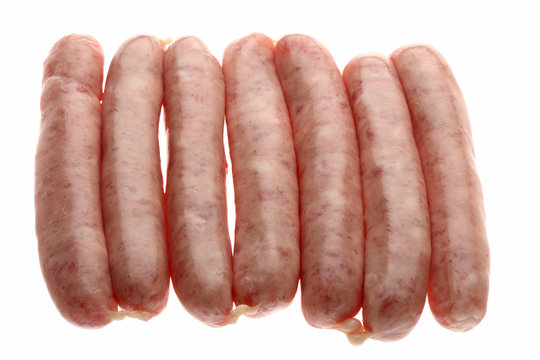 seven raw chipolata sausages on a white background
