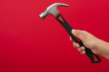 Hammer in hand on red background with copy space