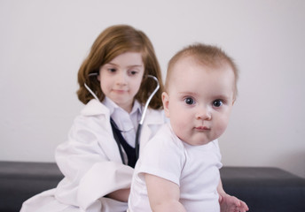 Little girl playing doctor with a baby (high-key).