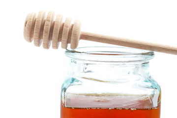 Honey jar and wooden drizzler, reflected on white background