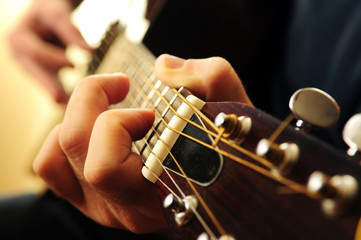 Hands of a person playing an acoustic guitar close up