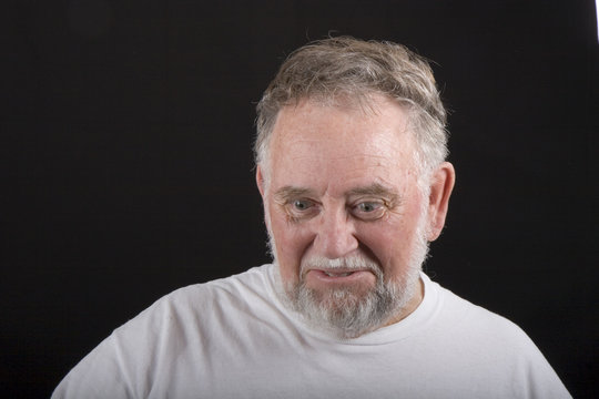 An Older Man In White Tshirt On A Black Background Looking Down