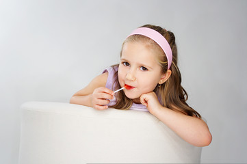 Nice young girl in pink on light background witn lollipop