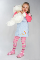 Nice young girl in pink on light background with teddy bear