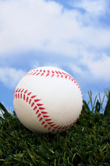Baseball sitting on grass with sky background with copy space