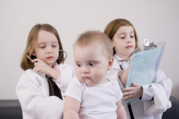 Three little girls playing doctor in a doctor's office.