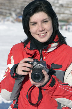 Attractive woman in sport wear holding a camera, winter outdoors