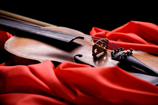 closeup of old violin on folded scarlet silk on black background