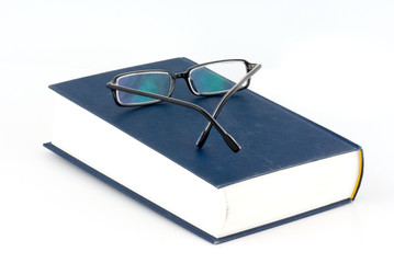 a book and a pair of glasses isolated on white