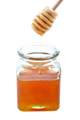 Pouring honey on glass jar, on white background