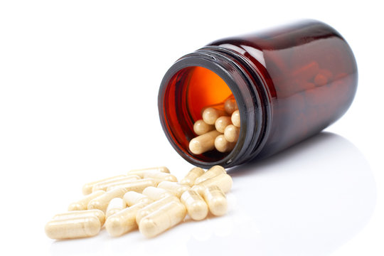 Capsules and  flask, shallow DOF. Reflected on white background