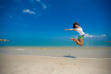 Fototapeta na wymiar young beautiful girl jumping happily at the beach