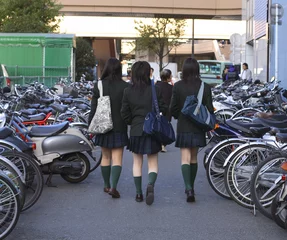 Gardinen Group of three japanese schoolgirls walking  in a city street. © Provisualstock.com