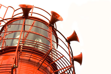 Bright red lighthouse with fog horns on white background