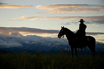 Cowboy silhouette against dawn sky