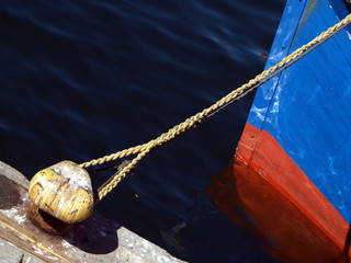 Prow of boat tied to cleat on harbourside with rope