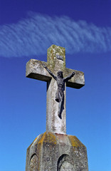 Old figure Christ on the stony cross - blue sky background