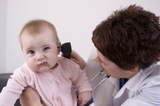 Pediatrician using an otoscope to look in a baby's ear.
