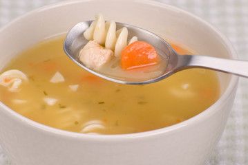 Chicken noodle soup with a spoon and bowl up close