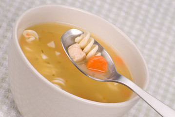 Chicken noodle soup with a spoon and bowl up close