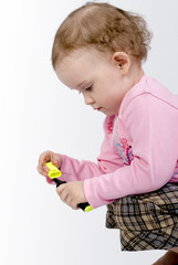 a sitting girl with dirty fingers is playing with a pencil