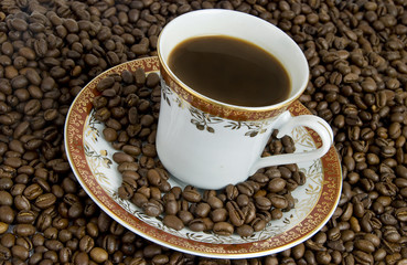 Hot drink of coffee with saucer and beans