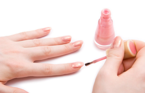 Young woman paint her nails. On white.