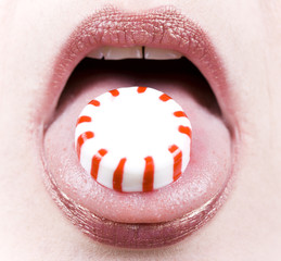 Naklejka premium Close-up of a peppermint candy on a woman's tongue
