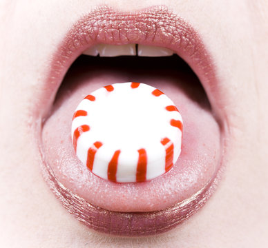 Close-up Of A Peppermint Candy On A Woman's Tongue