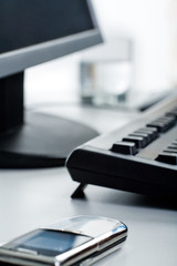 Telephone lying on a table with monitor, keyboard and glass 