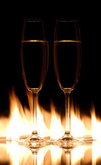 Two champagne glasses on fire with black background