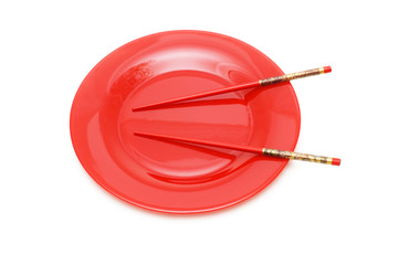 Red plate with chopsticks isolated on white