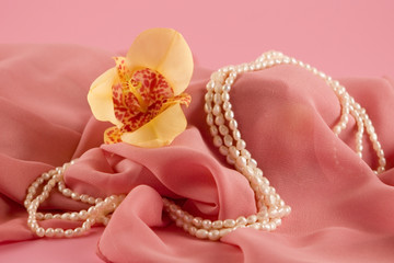 Yellow orchid and beads on a pink background