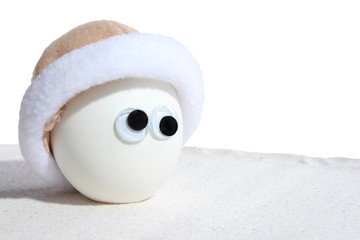 Egg with eyeballs and cap  on sand. Add own expressions