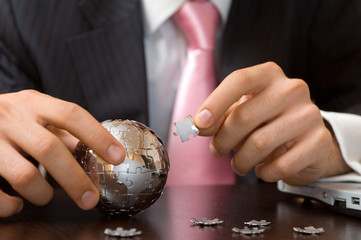  businessman playing a globe puzzle