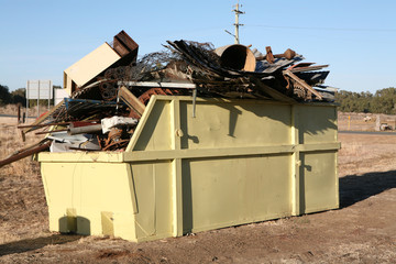 Yellow metal waste skip filled with household rubbish